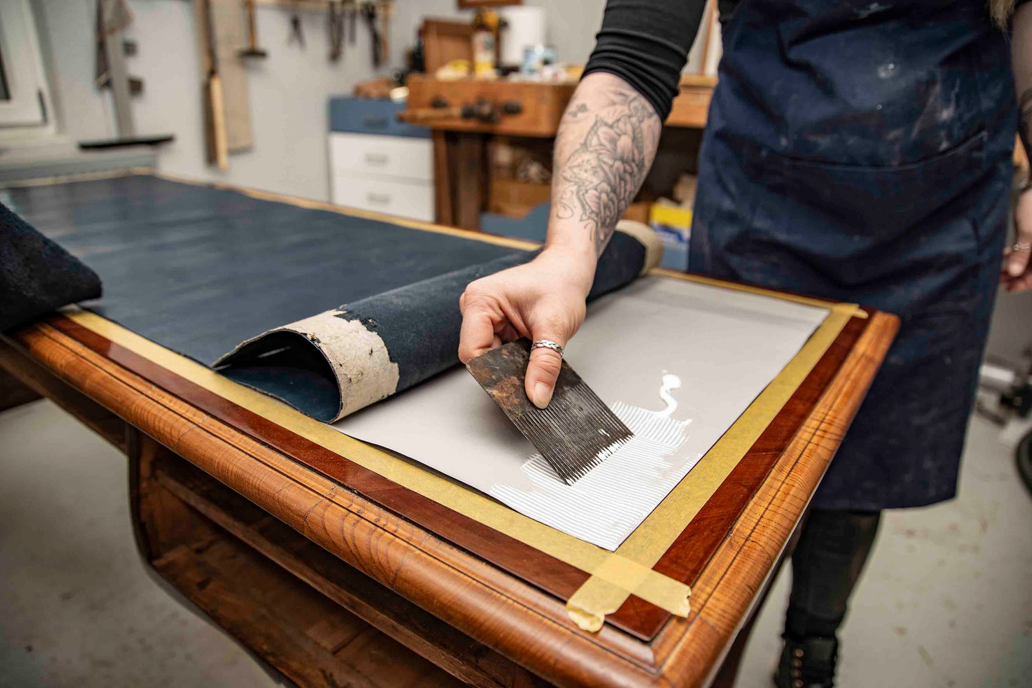 Restaurierung einer furnierten Tischoberfläche mit Leimauftrag in der Werkstatt von CARMINE HOME